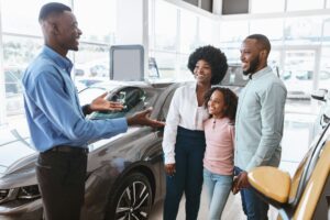 Car purchase or rental. Millennial black family with kid speaking to salesman